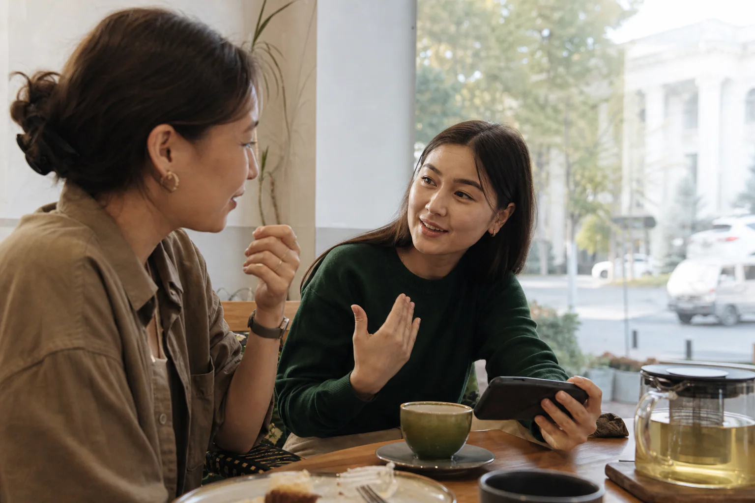 Two Kyrgyz women talking over tea in a contemporary Bishkek cafe.